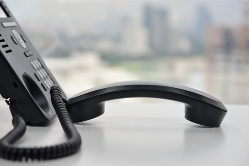 A close up shot of a phone with its handset off the hook. In the background a blurry city.